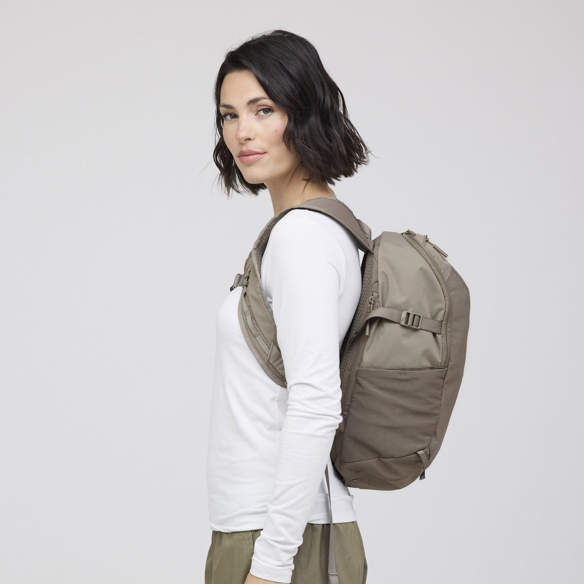 Woman wearing the taupe pack, three-quarter view showing how slim it sits on the back
