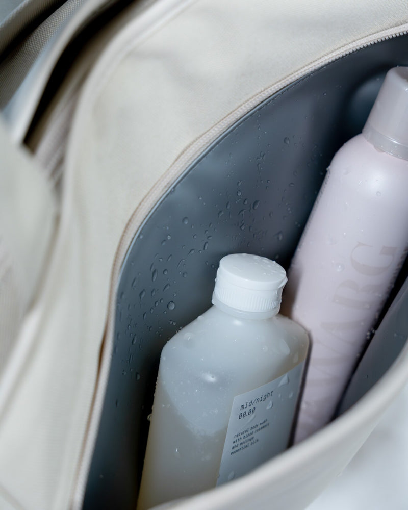 Front wet pocket of the sandstone Hellvi Pro Large open, water-repellent grey lining with shower gel and shampoo bottles