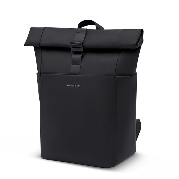 Kapten & Son Lund Sleek rolltop backpack in All Black, rolled, with the top handle and the hooked strap, three-quarter view
