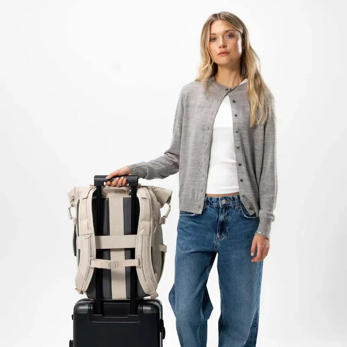 Woman holding suitcase with the Lisbon Pro sandstone attached — travel ready