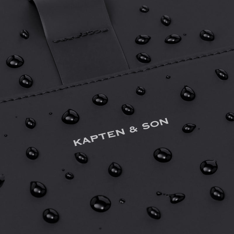 Close-up of water droplets beading on the smooth PU and the Kapten & Son logo, All Black