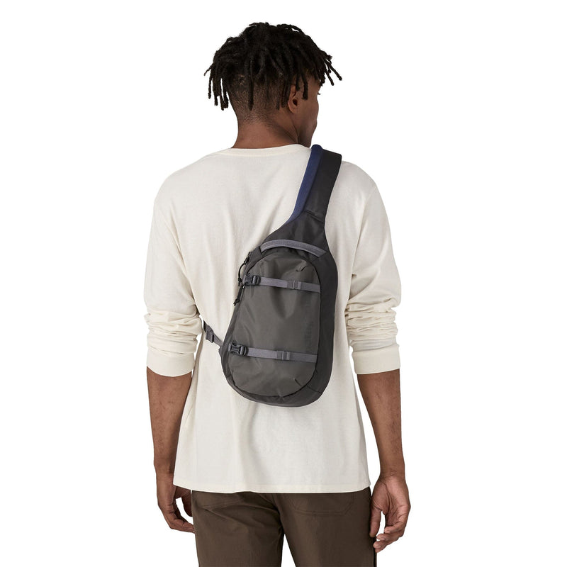 man model wearing the Atom Sling 8L in smolder blue, back view