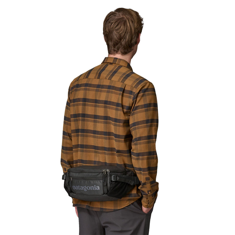 Man model wearing the Patagonia Black Hole Waist Pack 5L in Black as fanny pack on the back