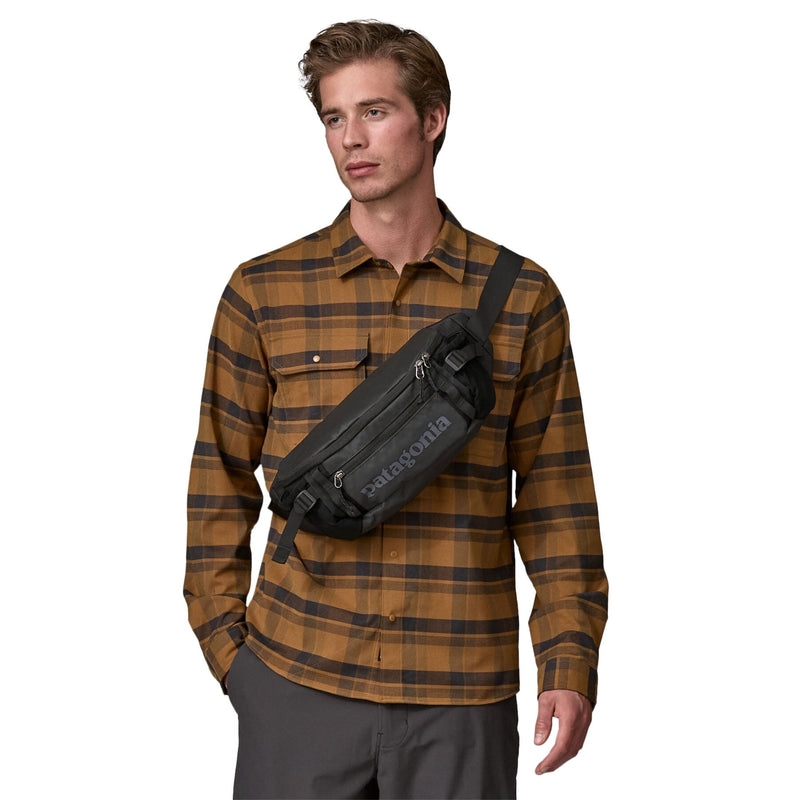 Man model wearing the Patagonia Black Hole Waist Pack 5L in Black as crossbody bag