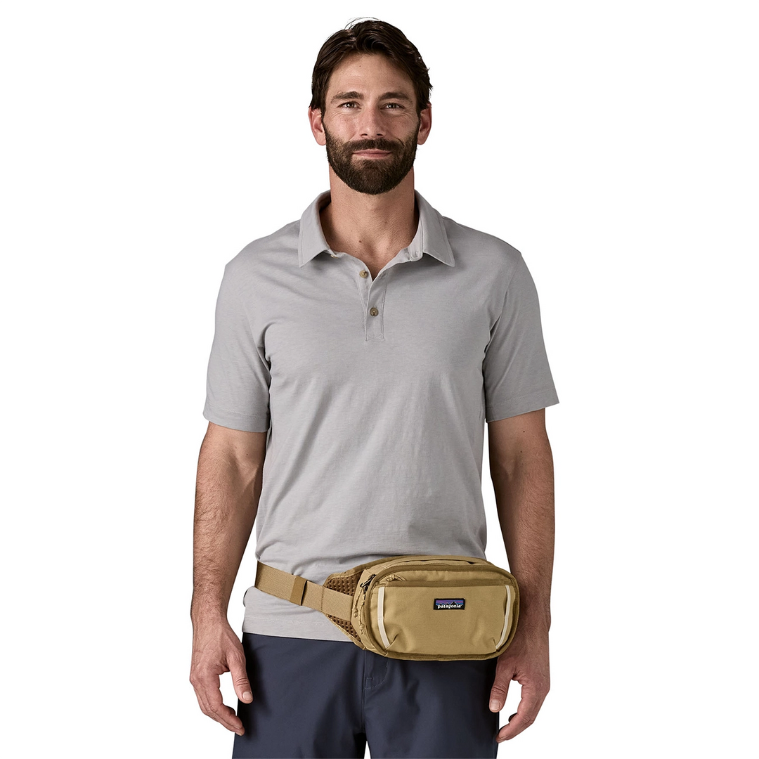 Man wearing the Fieldsmith Hip Pack 5L Classic Tan around the waist over a grey polo shirt
