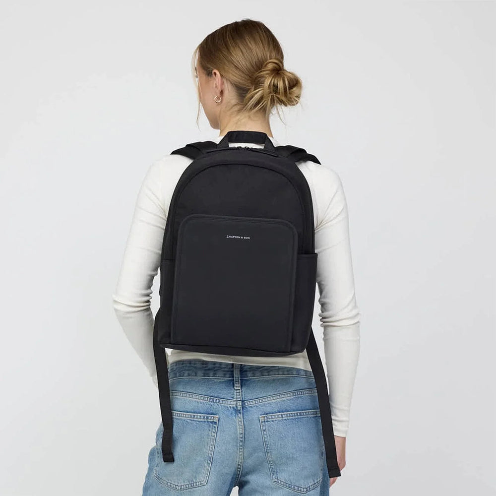 Woman wearing the Kapten & Son Aalborg backpack, rear view showing the compact everyday size