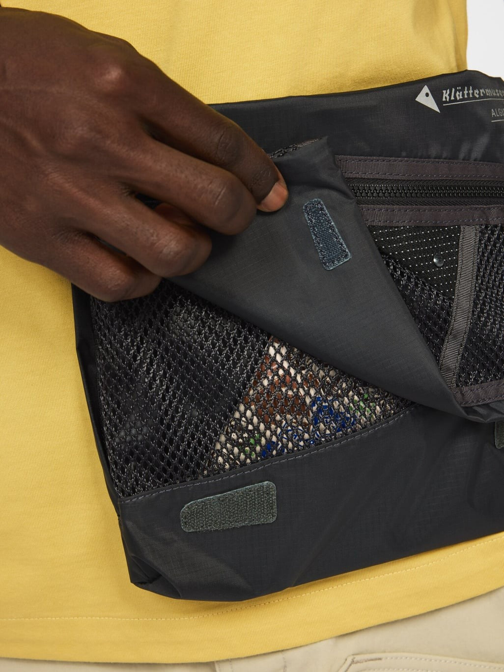 Foldover flap opened on the Algir Foldover Bag in Raven, mesh pocket underneath