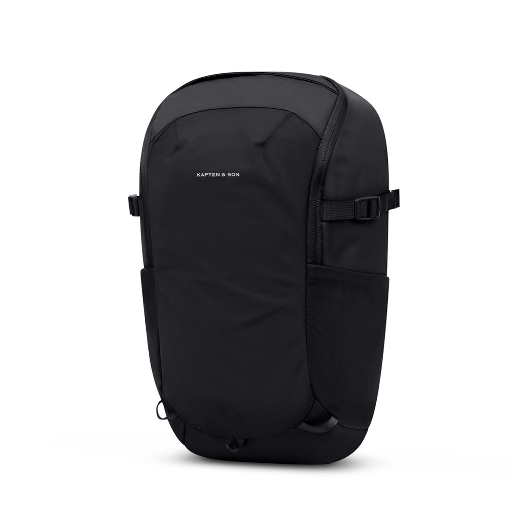 Black 13L daypack seen from a front three-quarter angle, showing the slim 13.5 cm depth