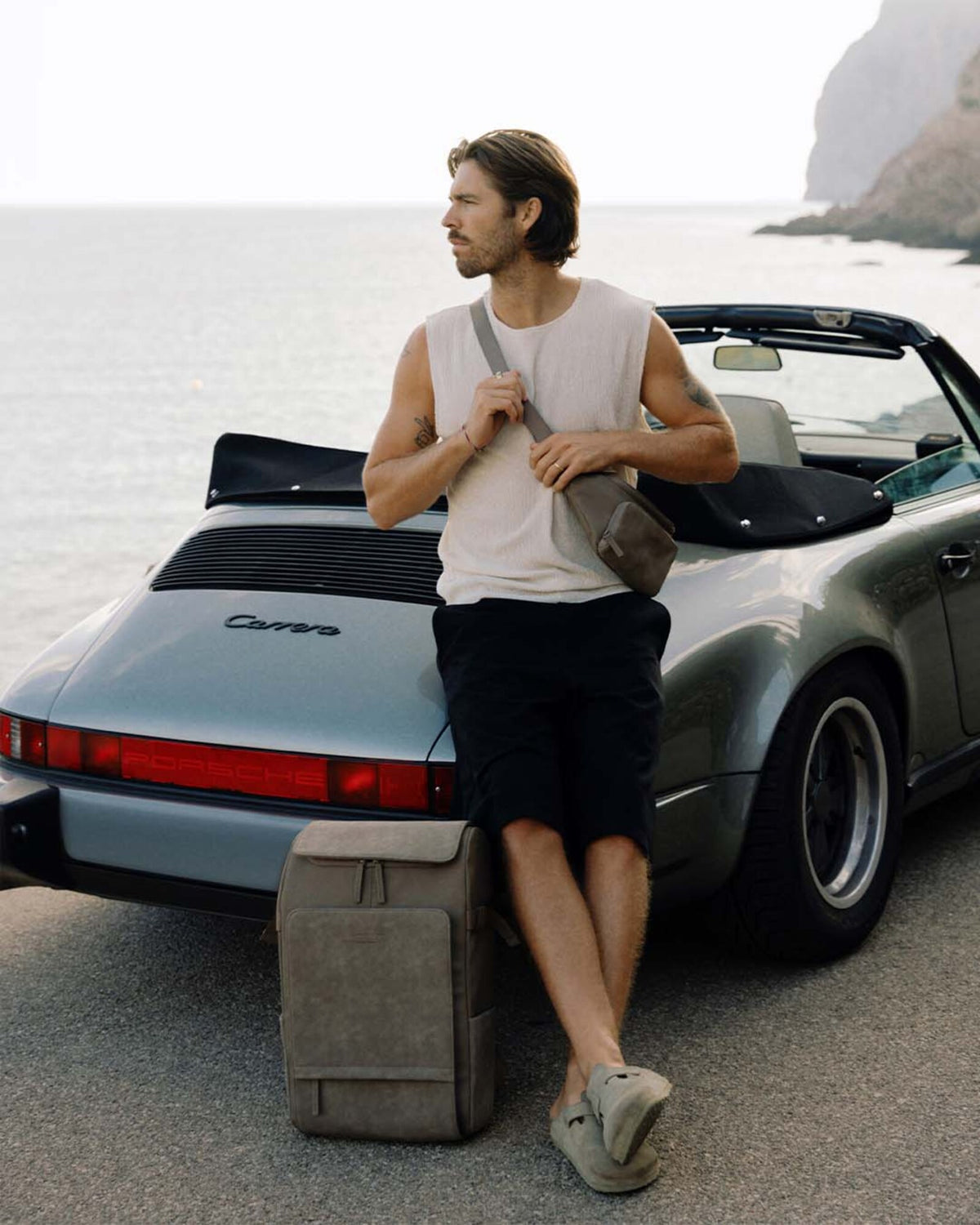 Man wearing the walnut Kapten & Son Bali Crossbody across the chest, by the sea