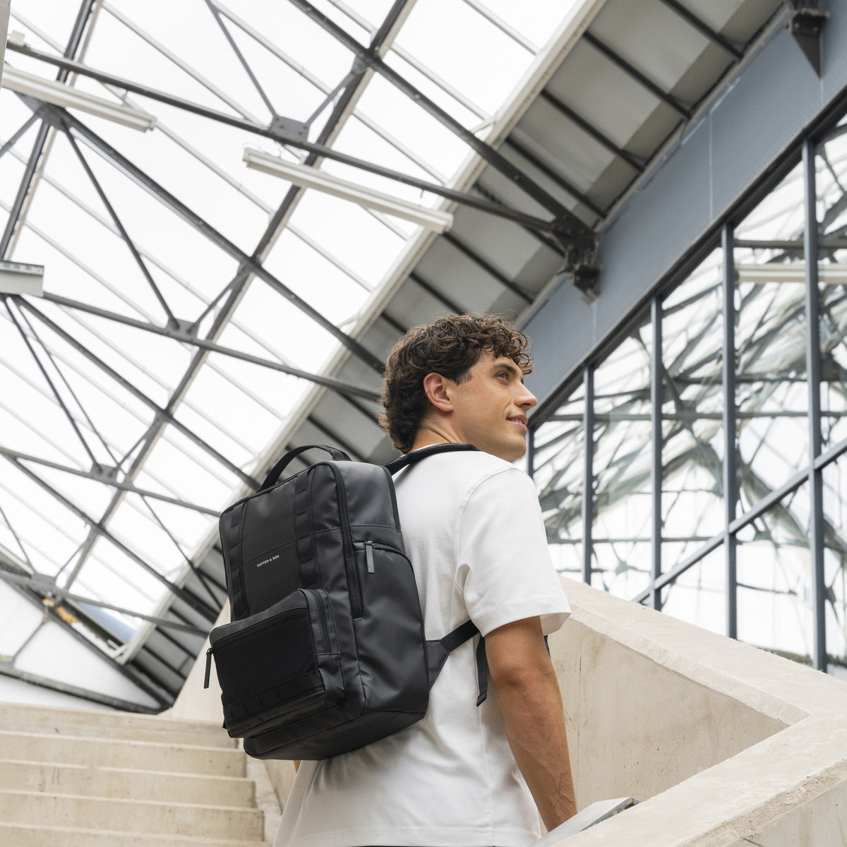 Commuter walking up stairs under a glass roof with the black Bergen Ultra