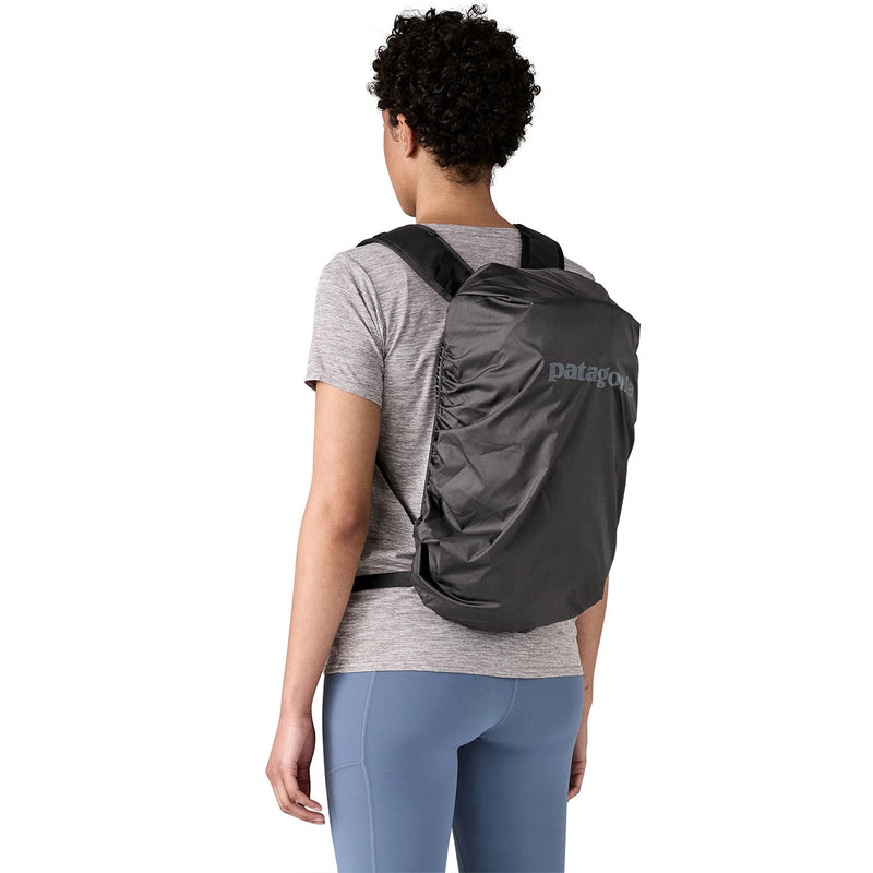 Trail-ready black daypack with rain cover deployed, worn for added weather protection