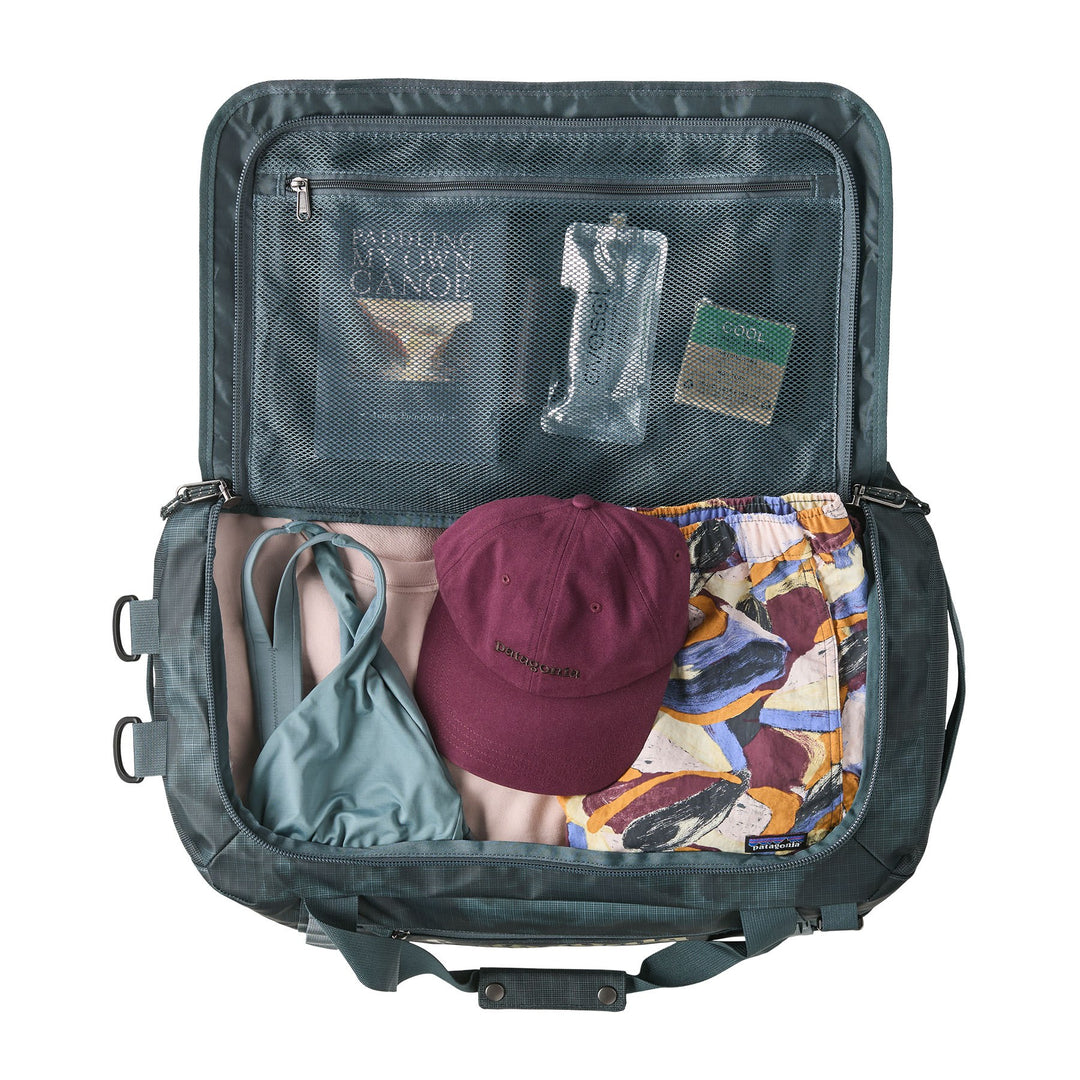 Open Black Hole Duffel 40L in Sastrugi Summit Blue packed with clothes, a cap and mesh lid pocket