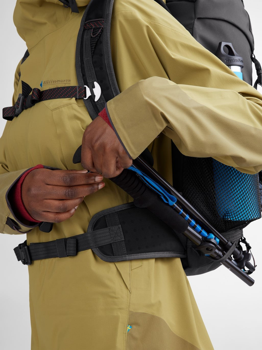Trekking poles stowed in the side holder of the Delling Backpack 30L in Raven