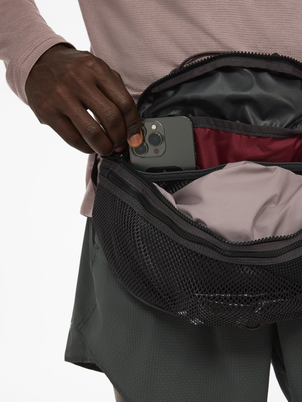 Phone slipped into the main zip pocket of the Eldrimner 5L in Raven, worn at the waist