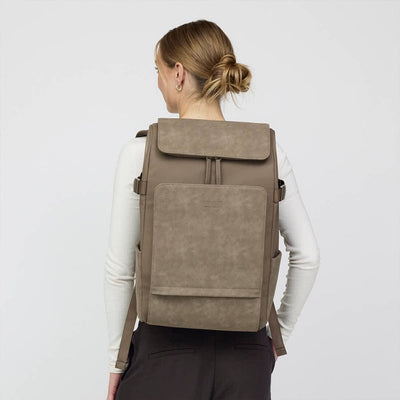 Modern vegan backpack worn by a woman on a neutral background, designed for daily commutes and smart organization