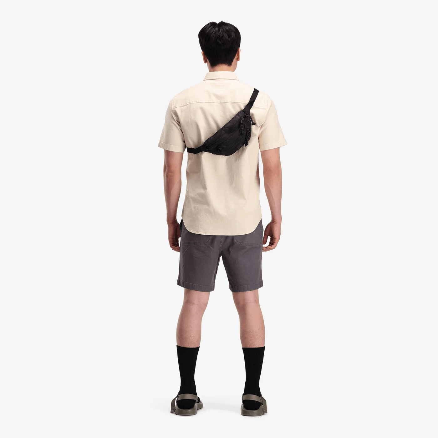 female hiker wearing black topo designs mountain waist pack as sling bag