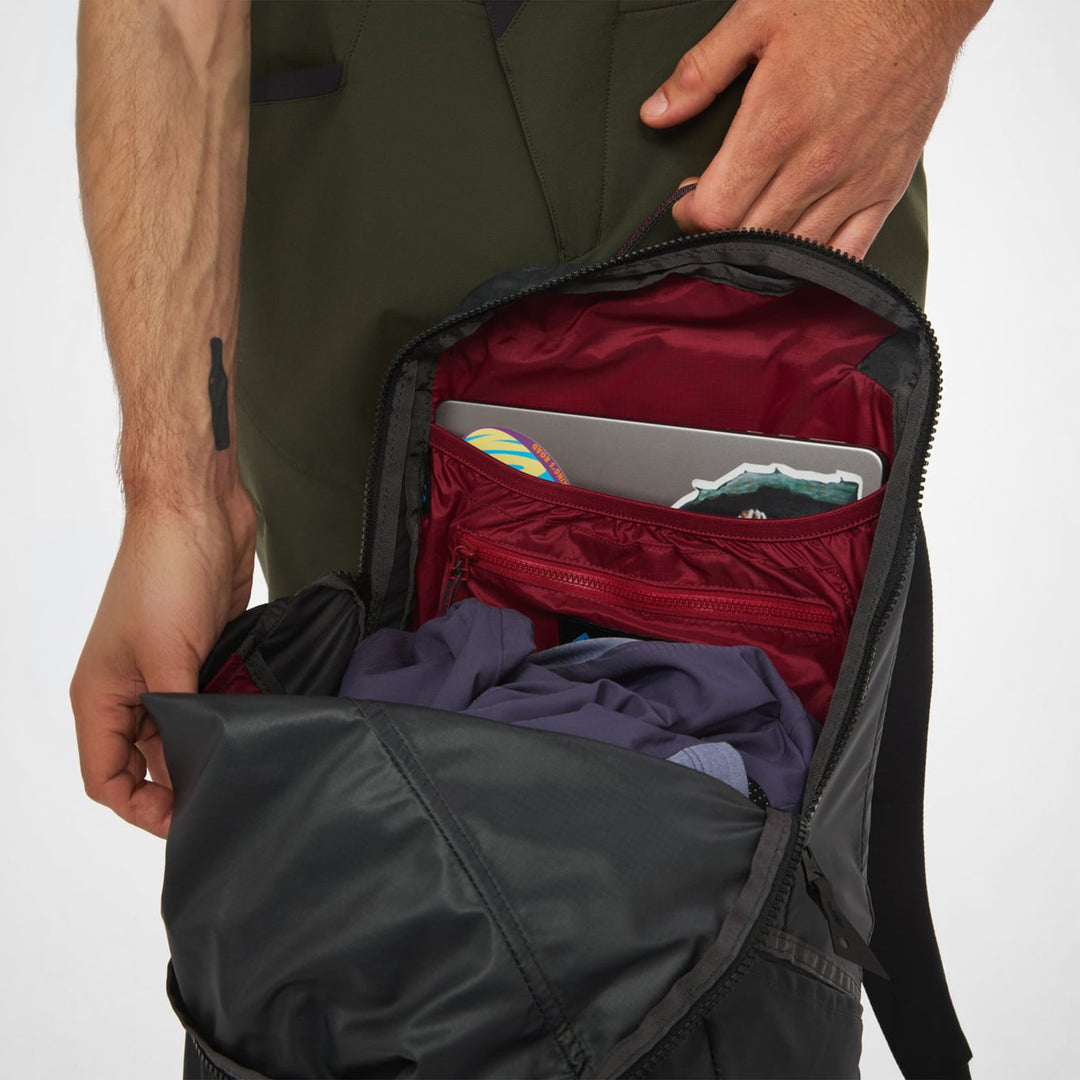 Gjalp 18L in Raven opened wide — main compartment with red lining holding a laptop and packed clothes