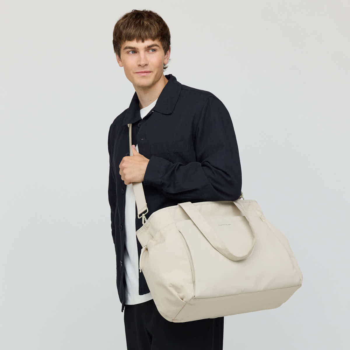 Man carrying the sandstone Hellvi Pro Large on the shoulder with its detachable strap