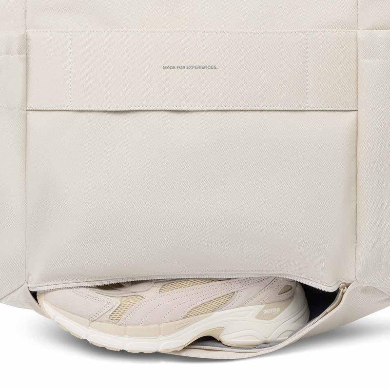 Zipped shoe compartment open at the base of the back of the sandstone Hellvi Pro Large, a sneaker inside