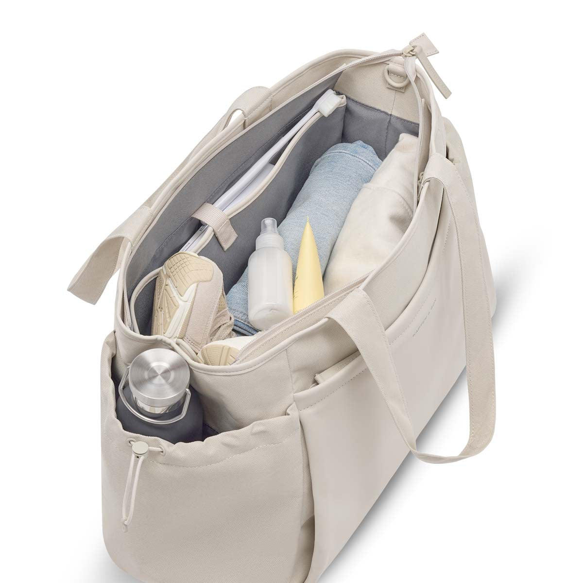 Sandstone Hellvi Pro Large open and packed: towel, clothes, shower bottles, a sneaker, and a steel bottle in the side pocket