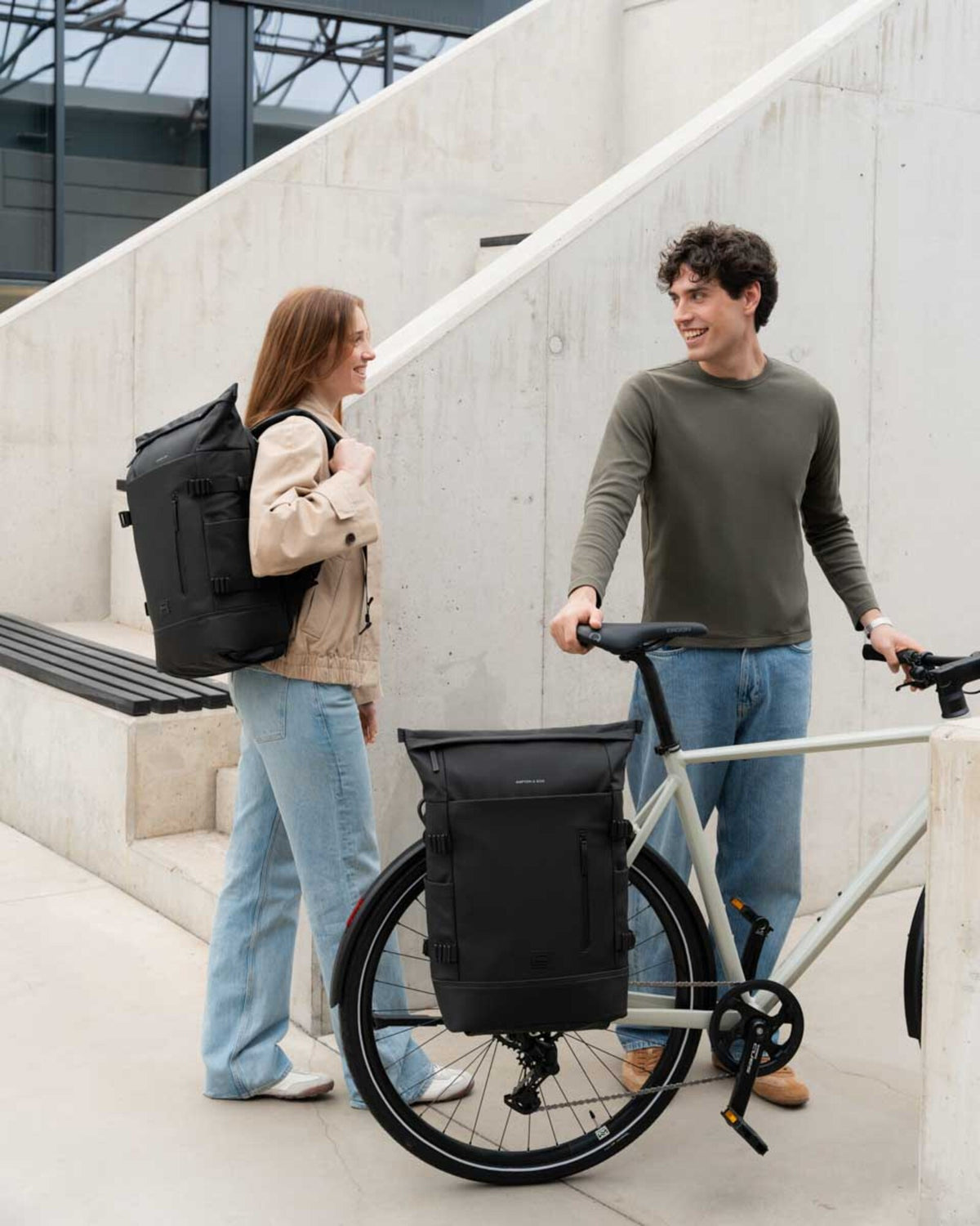 Woman wearing the Helsinki Pro Bike as a backpack, next to a man with the same bag clipped onto his bike rack