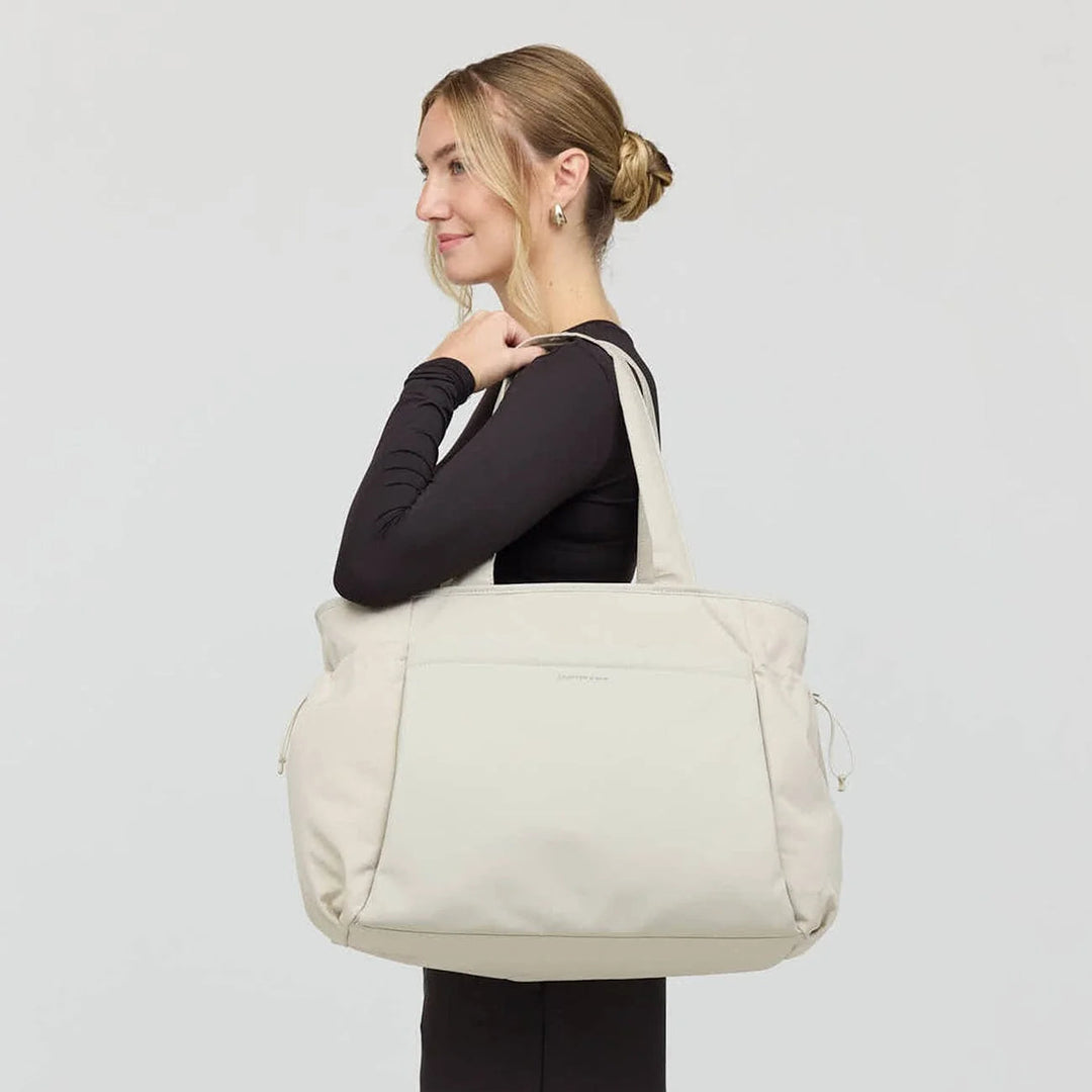 Woman carrying the Hellvi Large sandstone tote on shoulder — minimalist outfit