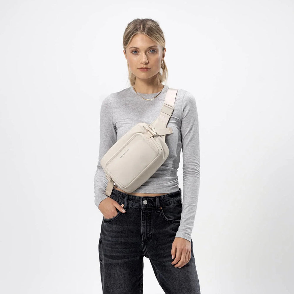 Woman wearing the Lisbon sandstone crossbody across chest — casual outfit
