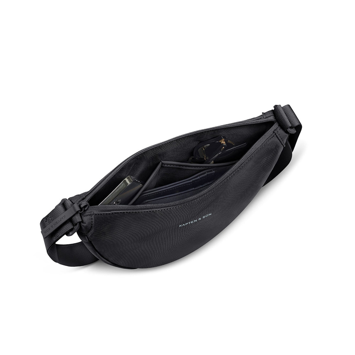 Black Essential Moon Bag open, holding a phone, a wallet and sunglasses