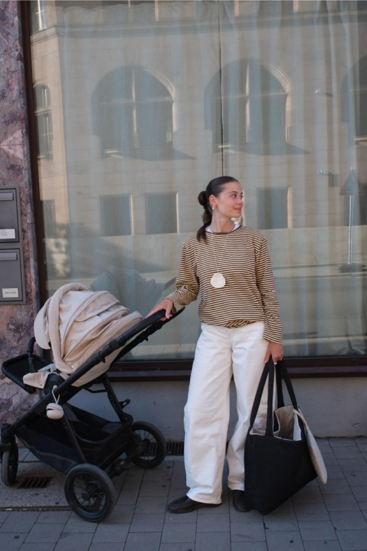 Woman holding the Norva 2in1 Shopper black side out, the sandstone Essentials Pouch hanging from one handle