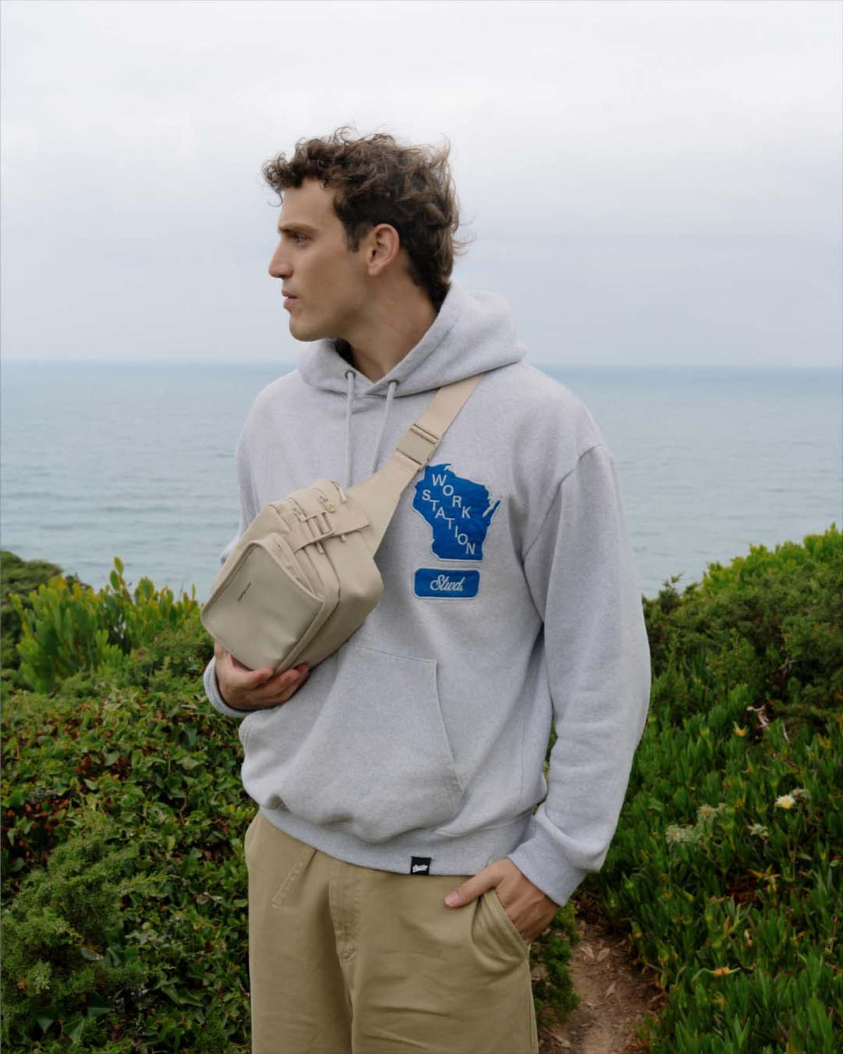 Man on the coast wearing the sandstone Lisbon Crossbody on his front
