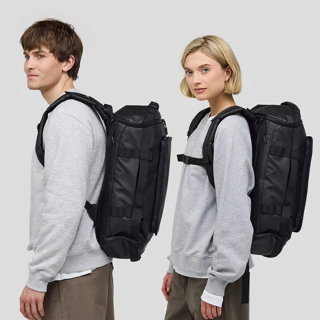Couple wearing the Lisbon Small duffle as a backpack — side view
