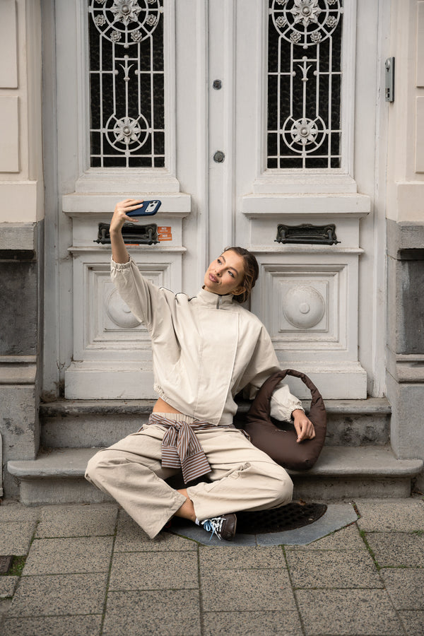 Woman taking a selfie on a doorstep, the chocolate brown Skara Cloud Shoulder beside her
