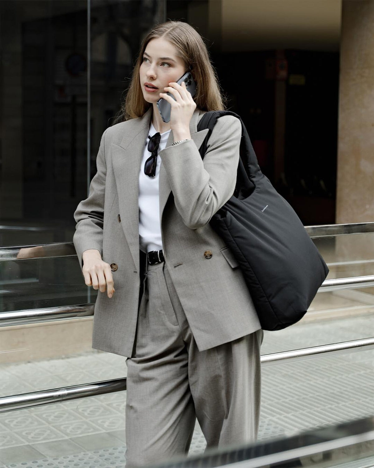 Woman on the phone in the street, the black Skara Cloud Tote on her shoulder