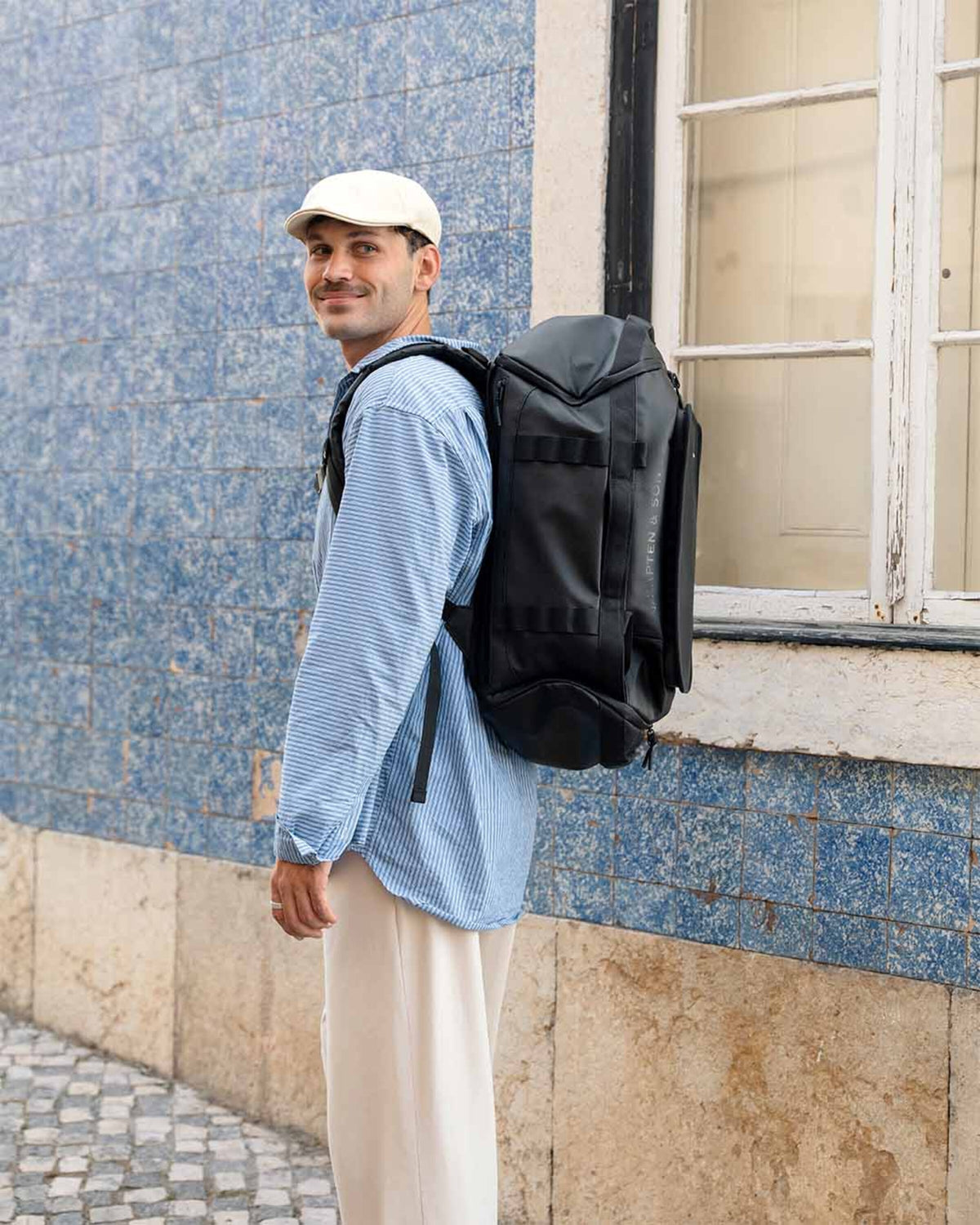 Man wearing the black Kapten & Son Lisbon Duffle Backpack Medium in front of a tiled wall