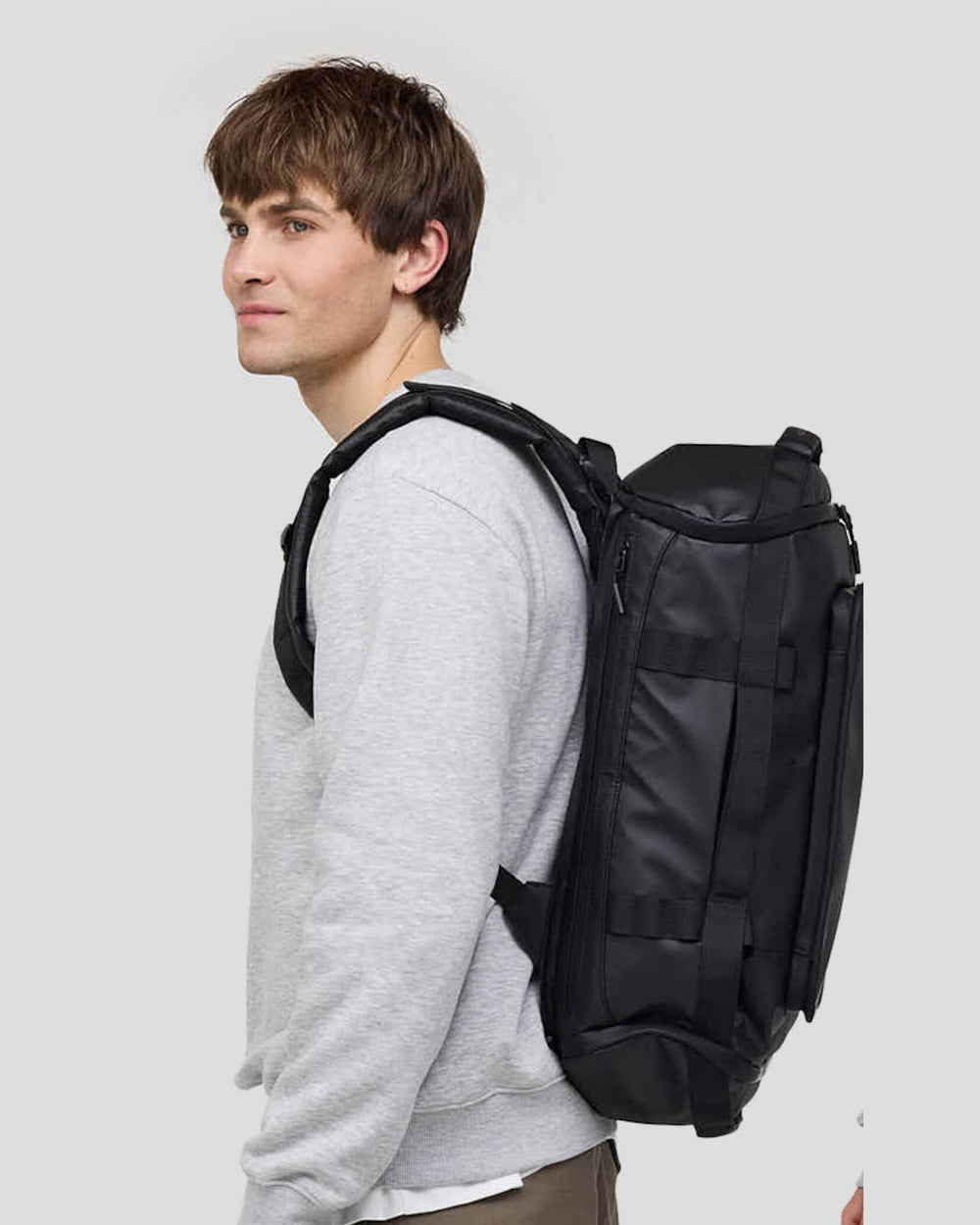 Felix, 1.85 m, wearing the black Lisbon Duffle Backpack Small, side view