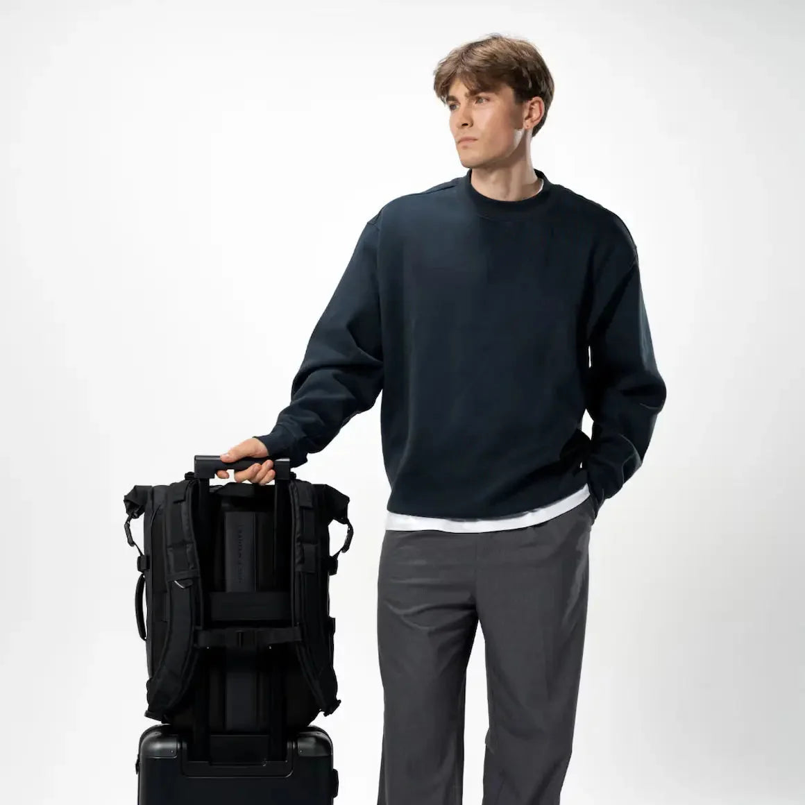 Man holding suitcase with the Lisbon Pro backpack attached — travel ready