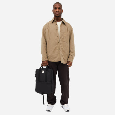 Man seen from the front holding an environmentally friendly black bag on a white background