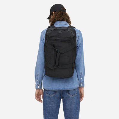 man wearing black convertible backpack made from recycled materials back view