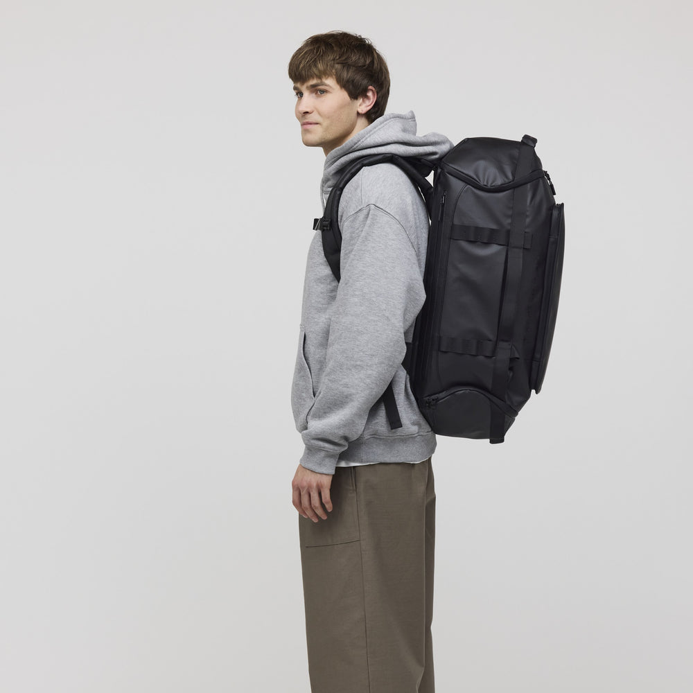Man wearing the black Lisbon Duffle Large, side profile