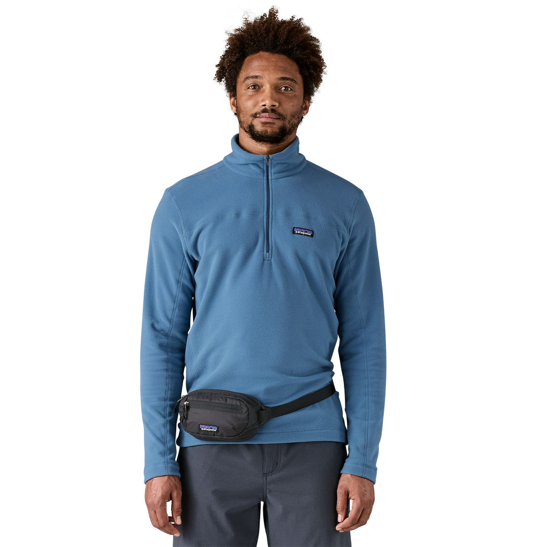 Man wearing the black Terravia Mini Hip Pack at the waist over a blue fleece pullover