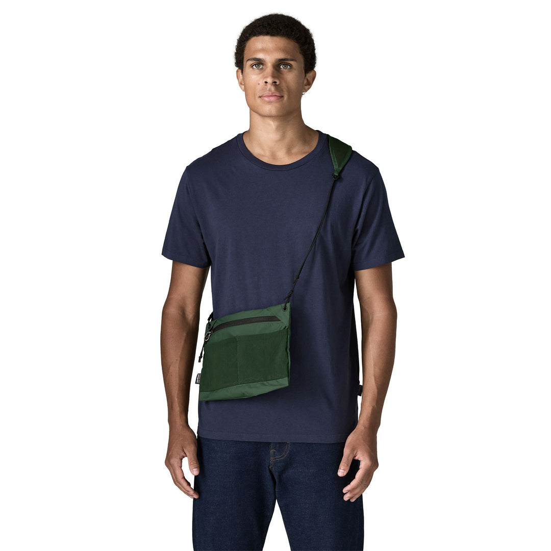 Man wearing the Terravia Sacoche 3L in Canopy Green crossbody over a navy t-shirt
