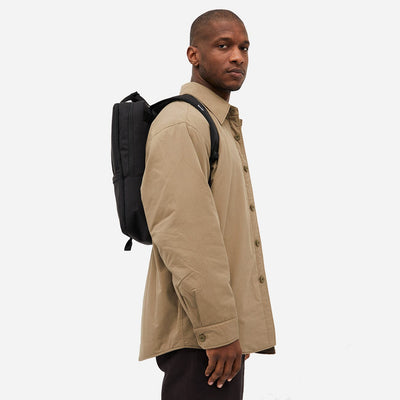 Side view of a man carrying a stylish black backpack on a white background