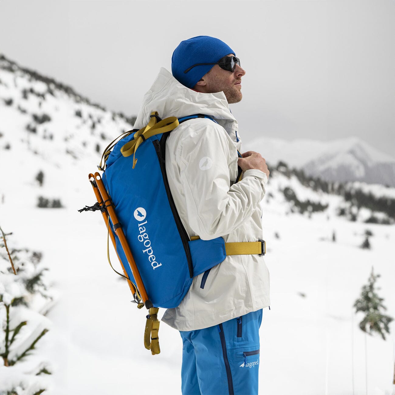 skier observing the mountain wearing lagoped's kiiruna2 in royal blue with two ice axes attached