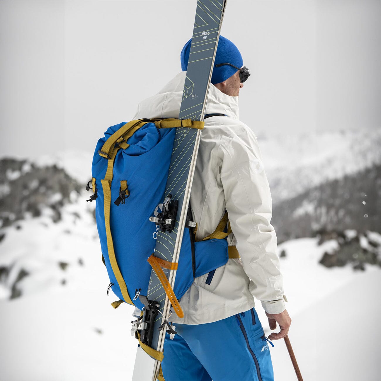 Touring skier carrying the Kiiruna 2 on his back with his skis attached to the bag using the dedicated mechanism