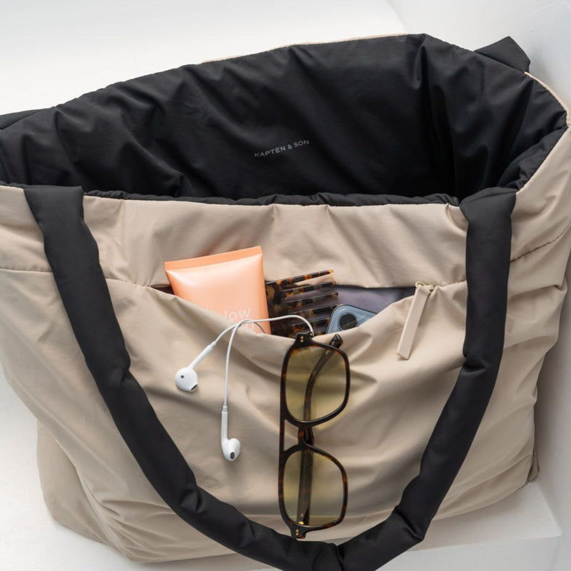 Close-up of the sand side, exterior zip pocket packed with sunglasses, earphones and hand cream