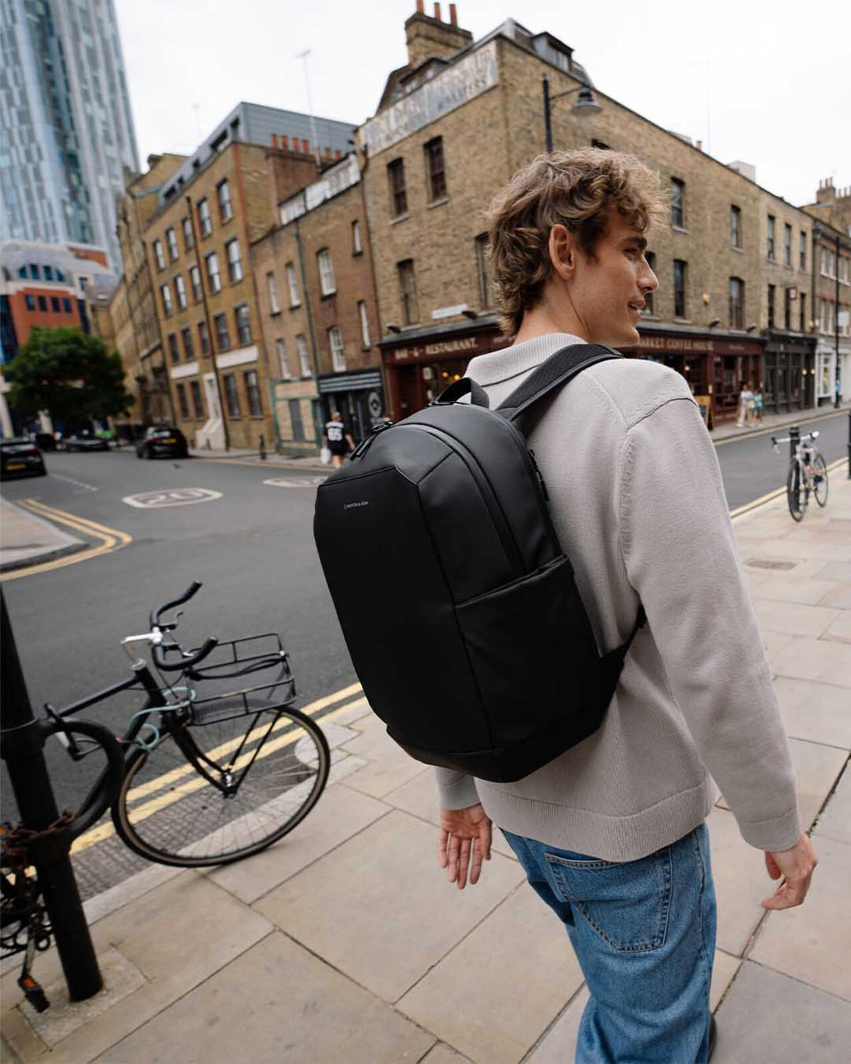 Man walking down a street wearing the black Kapten & Son Oslo backpack