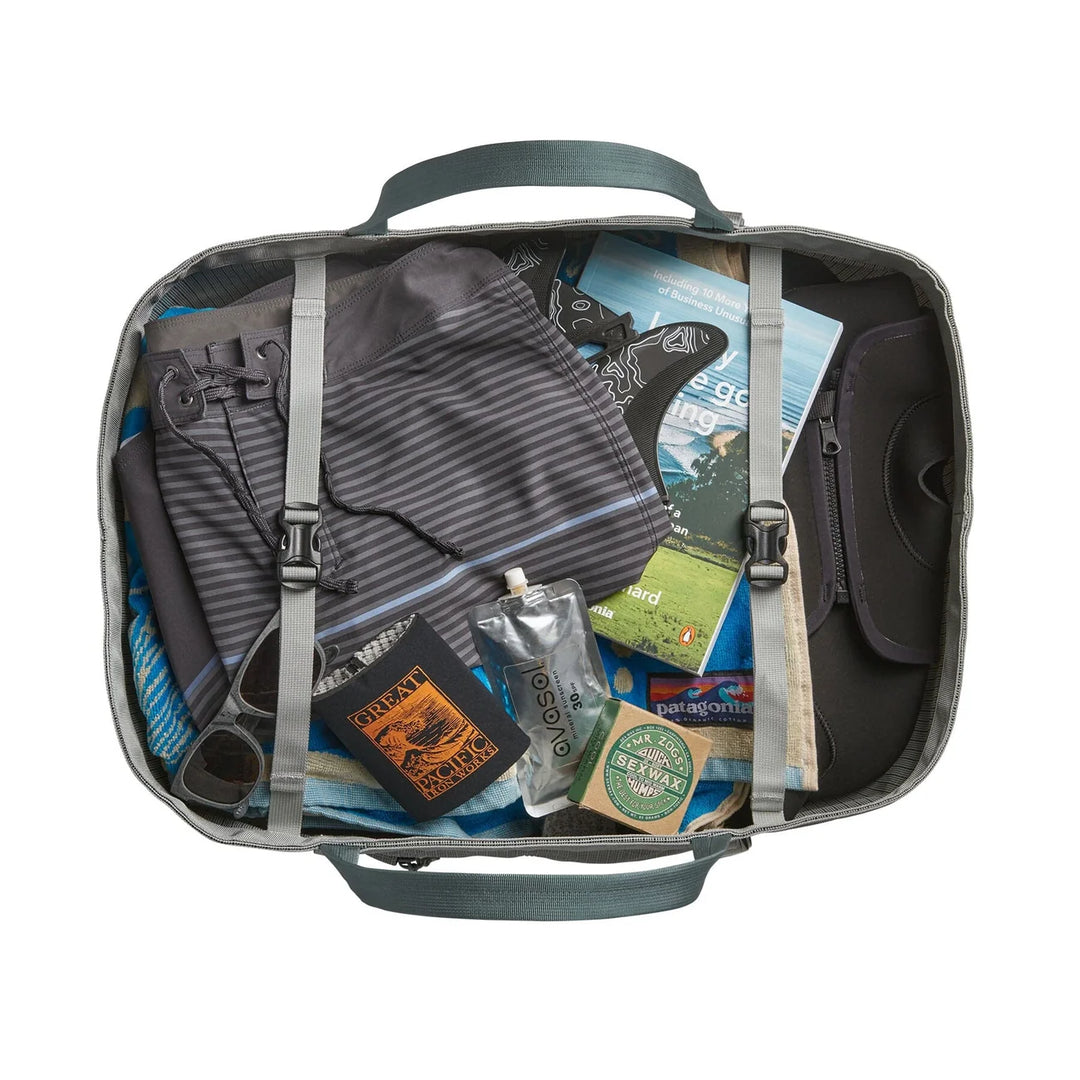 Top-down view of the open tote packed with clothes, wetsuit, books, and travel gear