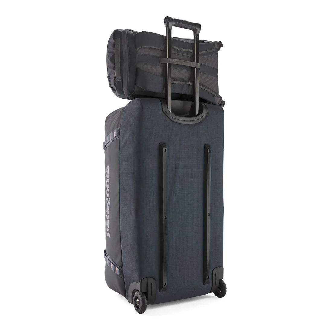 Black Hole Pack 25L mounted on a Patagonia roller bag using the rear pass-through sleeve