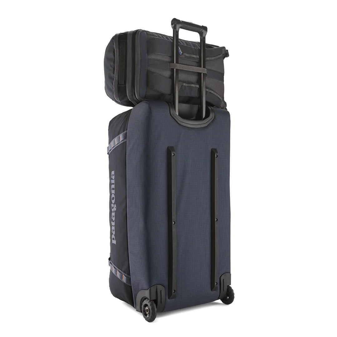 Black Hole Pack 32L mounted on a Patagonia roller bag using the rear pass-through sleeve