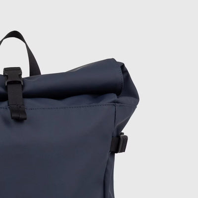 Rolltop closure of the navy blue slim backpack with buckle fastening, offering flexible storage and a minimalist waterproof design